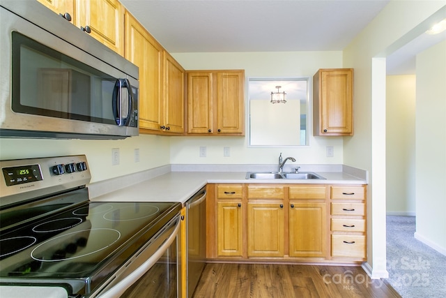 kitchen featuring dark wood-type flooring, appliances with stainless steel finishes, light countertops, and a sink