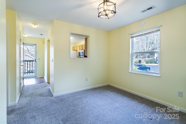 carpeted spare room featuring visible vents, a notable chandelier, and baseboards