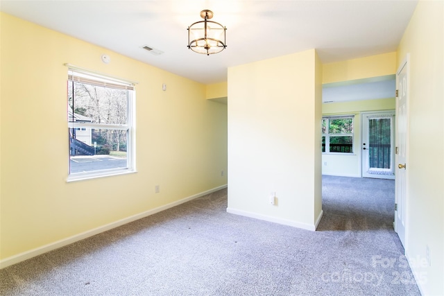 unfurnished room featuring a chandelier, dark colored carpet, visible vents, and baseboards