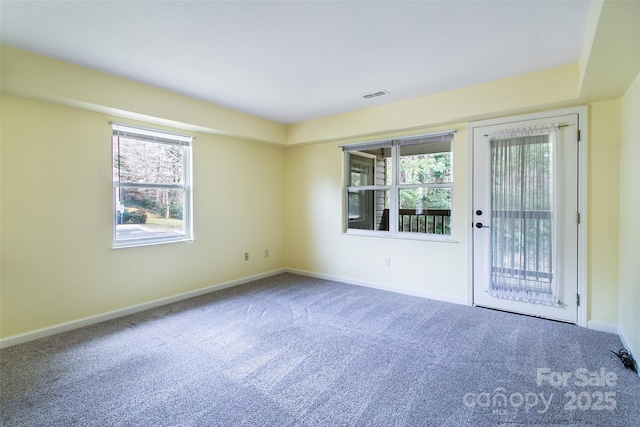 carpeted empty room with a healthy amount of sunlight, baseboards, and visible vents