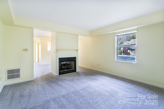 unfurnished living room with baseboards, a fireplace, visible vents, and light colored carpet