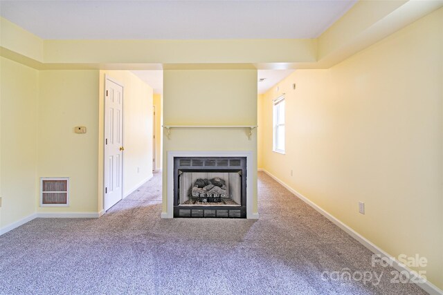 unfurnished living room featuring a fireplace, carpet flooring, visible vents, and baseboards