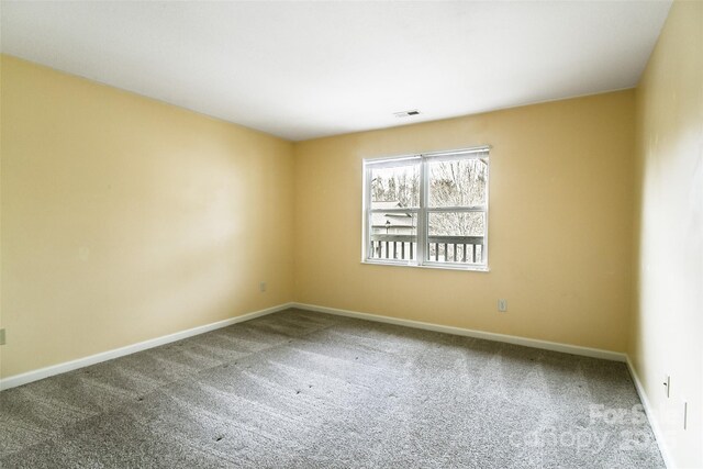 unfurnished room featuring carpet, visible vents, and baseboards