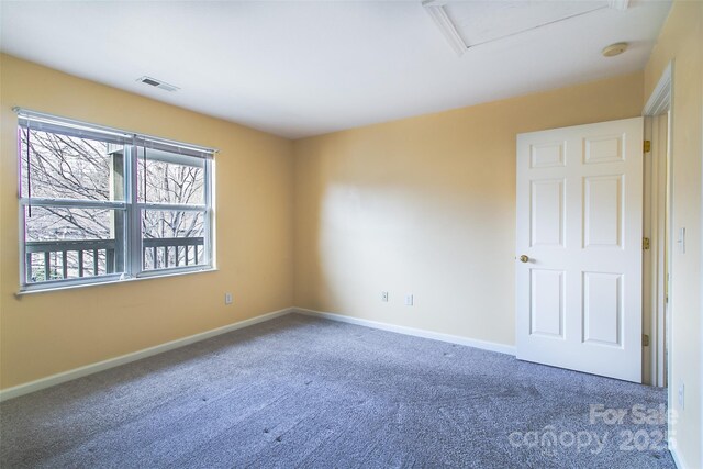 carpeted empty room featuring visible vents and baseboards