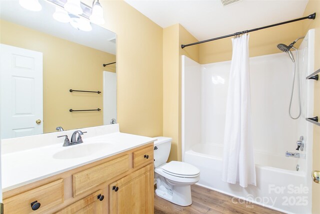 full bathroom with visible vents, toilet, shower / tub combo with curtain, wood finished floors, and vanity