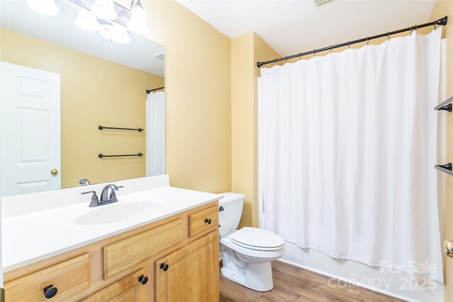 bathroom with visible vents, toilet, shower / tub combo, vanity, and wood finished floors