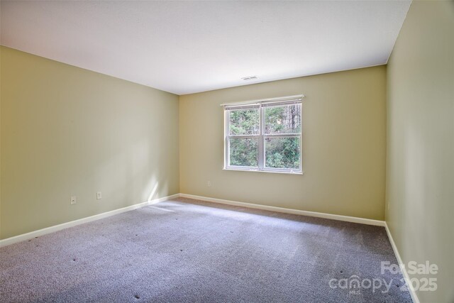 carpeted spare room with visible vents and baseboards