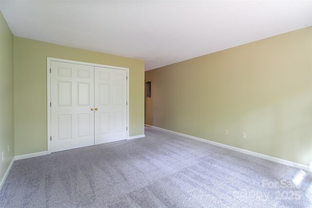 unfurnished bedroom with a closet, carpet flooring, and baseboards