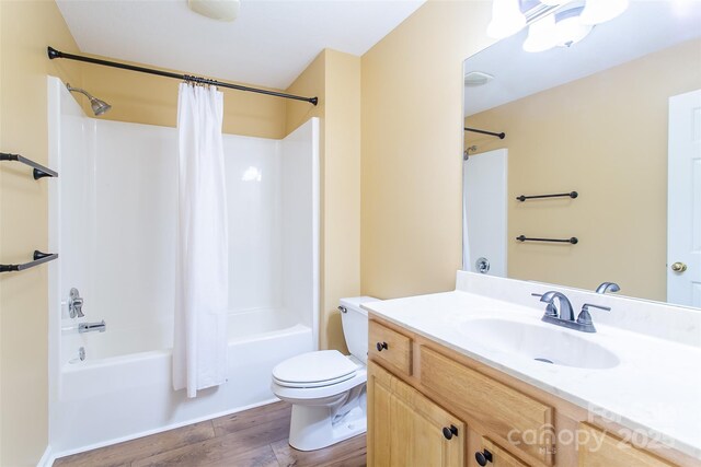 full bathroom with toilet, shower / tub combo, wood finished floors, and vanity