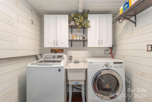 laundry room with washer and dryer, cabinets, and wooden walls