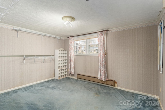 carpeted spare room featuring a textured ceiling and a baseboard heating unit