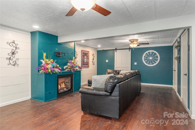 living room with a textured ceiling, a barn door, ceiling fan, and dark hardwood / wood-style floors