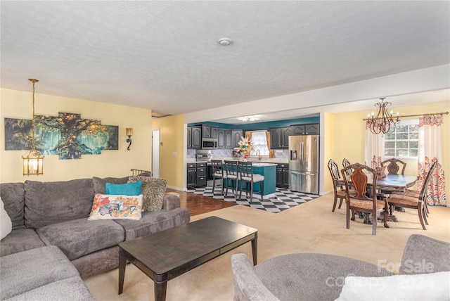 living room with sink, light colored carpet, a textured ceiling, and a chandelier