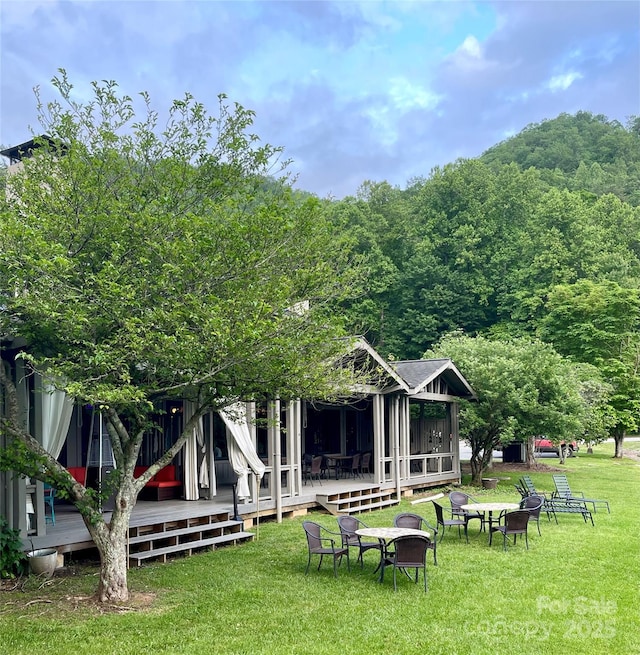 back of property featuring a fire pit, a deck, and a lawn