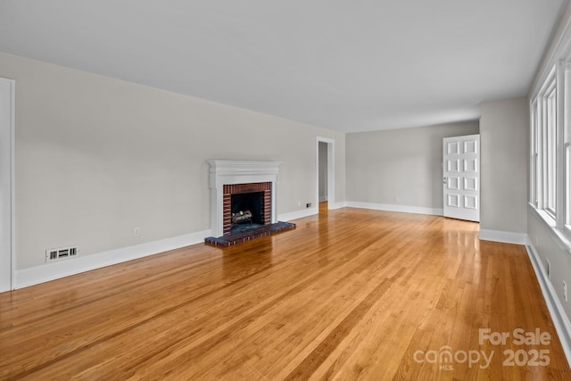 unfurnished living room featuring light hardwood / wood-style floors and a brick fireplace