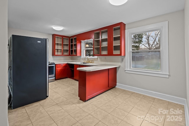 kitchen with black refrigerator, light tile patterned floors, tasteful backsplash, and stainless steel range oven