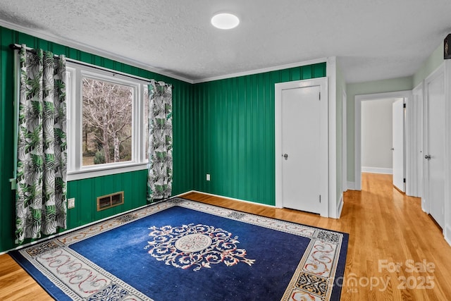 unfurnished room with wood-type flooring, a textured ceiling, and crown molding