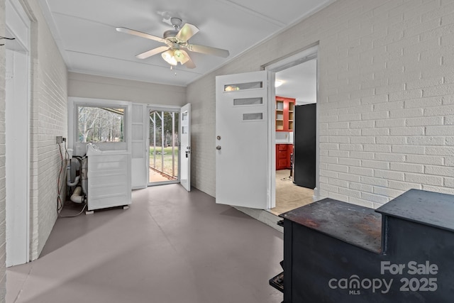 foyer with ceiling fan, concrete floors, and brick wall