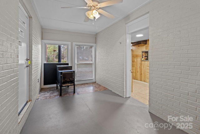 sunroom featuring ceiling fan and a wood stove