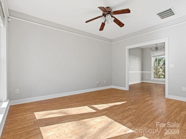 empty room with hardwood / wood-style floors and ceiling fan with notable chandelier