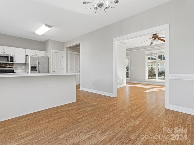 kitchen with white cabinetry, stainless steel appliances, ceiling fan with notable chandelier, and light hardwood / wood-style floors