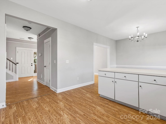 unfurnished dining area featuring light hardwood / wood-style floors and a notable chandelier