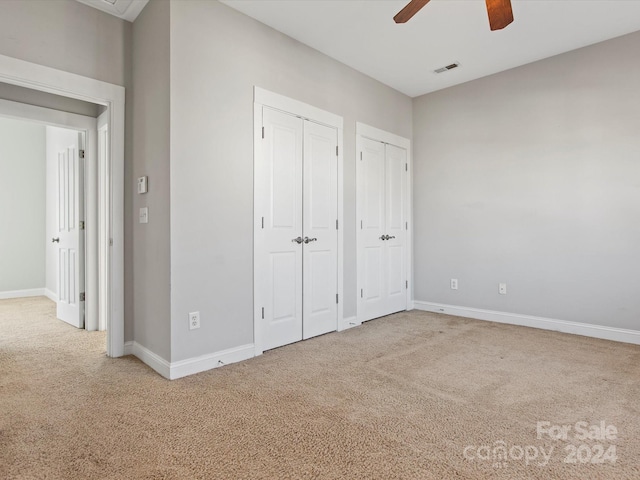 unfurnished bedroom with carpet flooring, multiple closets, and ceiling fan