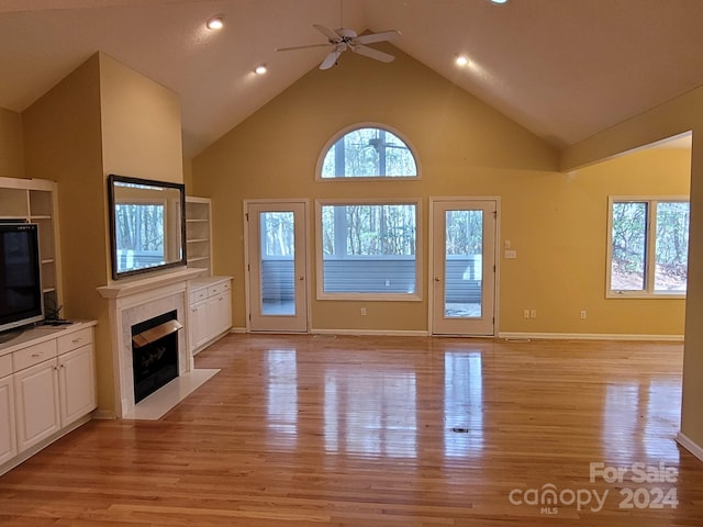 unfurnished living room featuring ceiling fan, light hardwood / wood-style flooring, high vaulted ceiling, and a healthy amount of sunlight