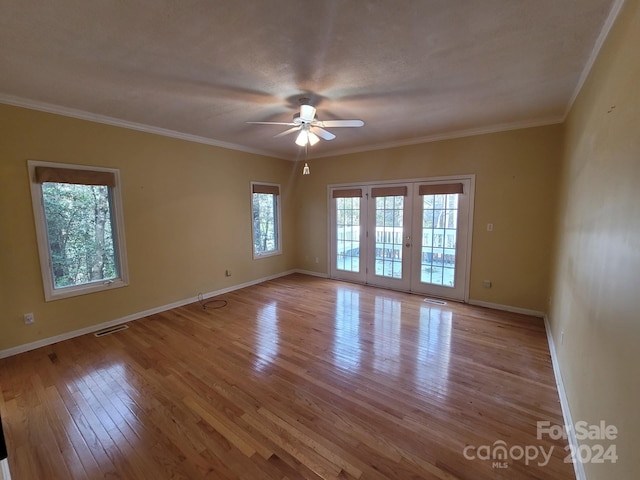 empty room featuring ceiling fan, crown molding, a healthy amount of sunlight, and light wood-type flooring