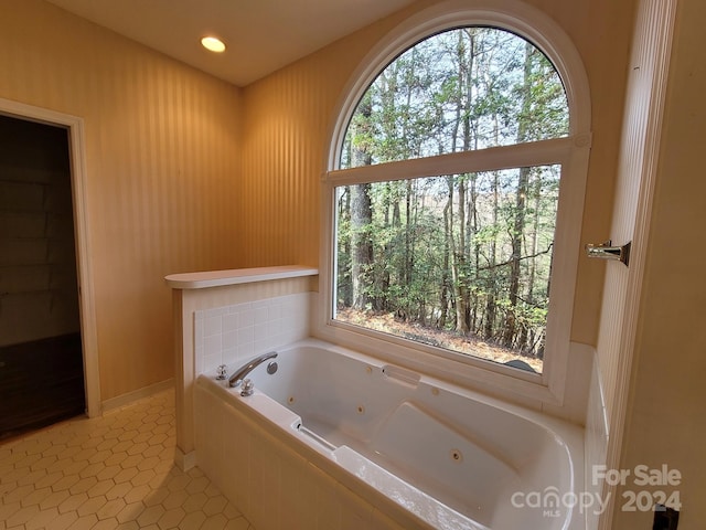 bathroom with tiled tub and tile patterned flooring