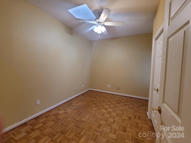 spare room featuring a skylight, light parquet flooring, and a textured ceiling