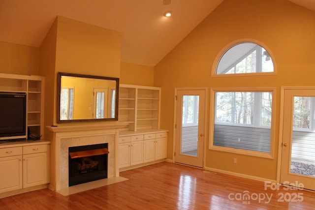 unfurnished living room with high vaulted ceiling and light wood-type flooring