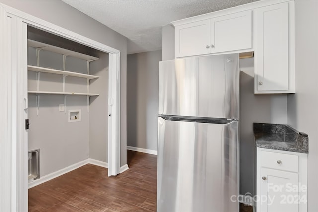 kitchen with a textured ceiling, white cabinetry, dark wood-type flooring, and stainless steel refrigerator