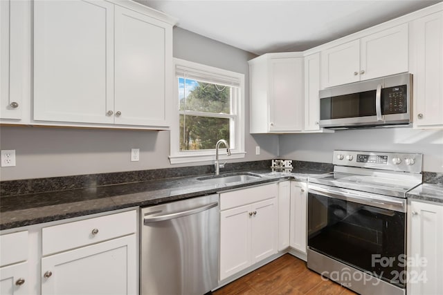 kitchen with appliances with stainless steel finishes, dark hardwood / wood-style flooring, white cabinetry, and sink