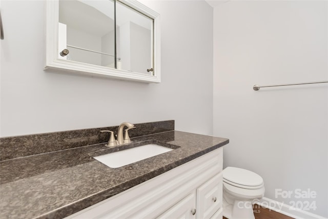 bathroom with toilet, vanity, and hardwood / wood-style flooring