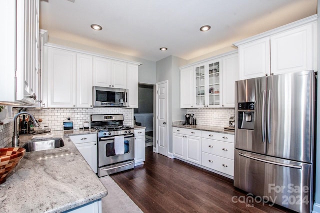 kitchen with white cabinetry, sink, light stone countertops, dark hardwood / wood-style floors, and appliances with stainless steel finishes