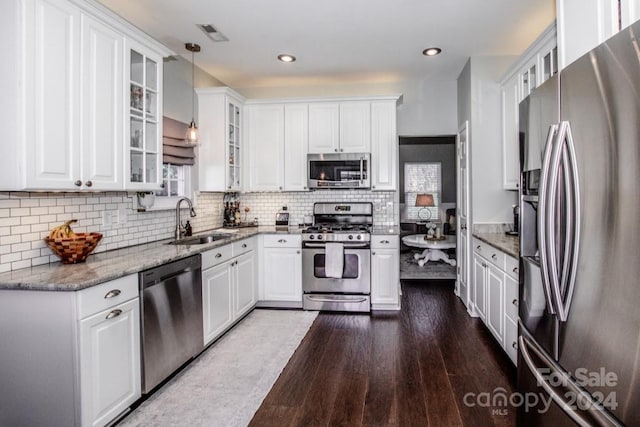 kitchen with pendant lighting, stainless steel appliances, white cabinetry, and dark wood-type flooring