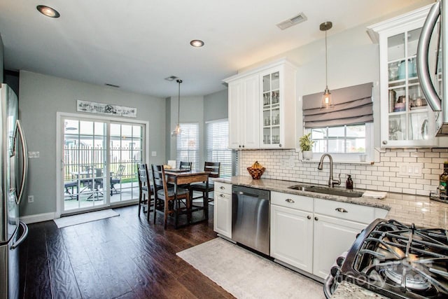 kitchen with light stone countertops, appliances with stainless steel finishes, white cabinetry, and hanging light fixtures