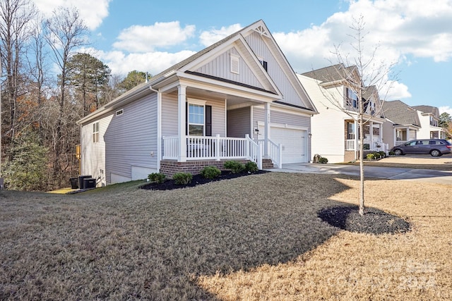 view of front of property featuring central air condition unit, covered porch, a front yard, and a garage