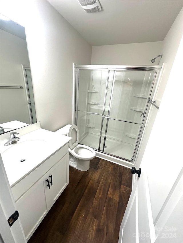 bathroom featuring hardwood / wood-style flooring, vanity, toilet, and an enclosed shower