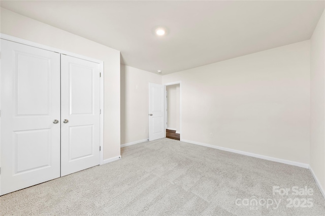 unfurnished bedroom featuring light carpet and a closet