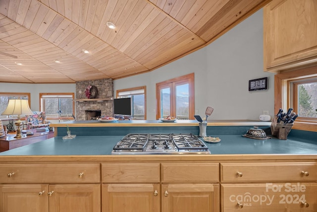 kitchen featuring light brown cabinetry, wood ceiling, a fireplace, and stainless steel gas cooktop