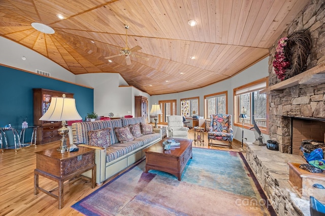 living room featuring a stone fireplace, ceiling fan, hardwood / wood-style floors, and wood ceiling