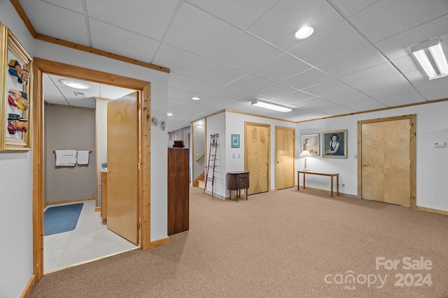 basement featuring a paneled ceiling, crown molding, and light carpet