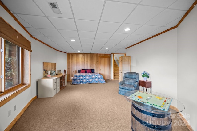 bedroom with carpet flooring, a drop ceiling, ornamental molding, and wooden walls