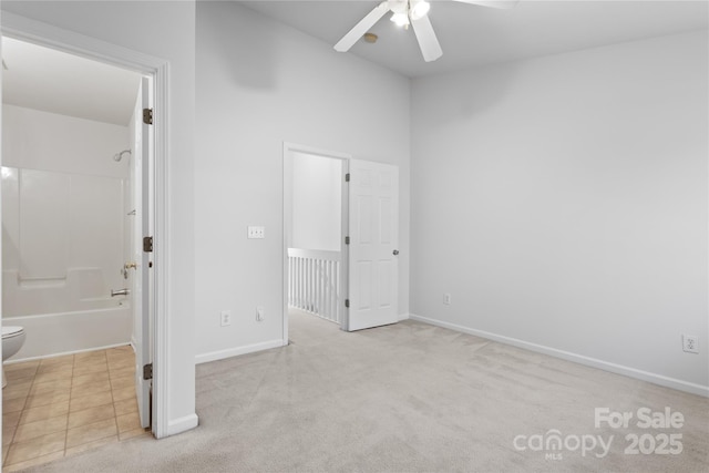 unfurnished bedroom with ensuite bathroom, light colored carpet, and ceiling fan