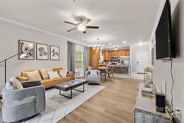 living room featuring ceiling fan with notable chandelier, light hardwood / wood-style floors, and crown molding