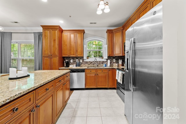 kitchen featuring backsplash, crown molding, sink, light stone countertops, and stainless steel appliances