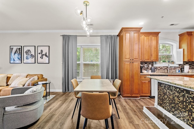 dining room with ornamental molding, a healthy amount of sunlight, and hardwood / wood-style flooring