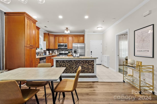 kitchen with a center island, stainless steel appliances, light wood-type flooring, and ornamental molding